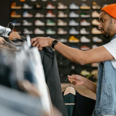 Man shopping for jackets in a trendy fashion store with skateboard decor.