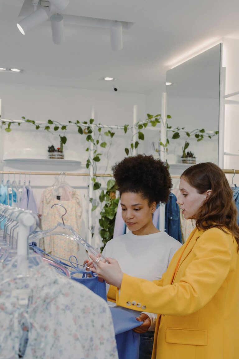Two women shopping for clothes in a modern boutique, guided by a personal stylist.