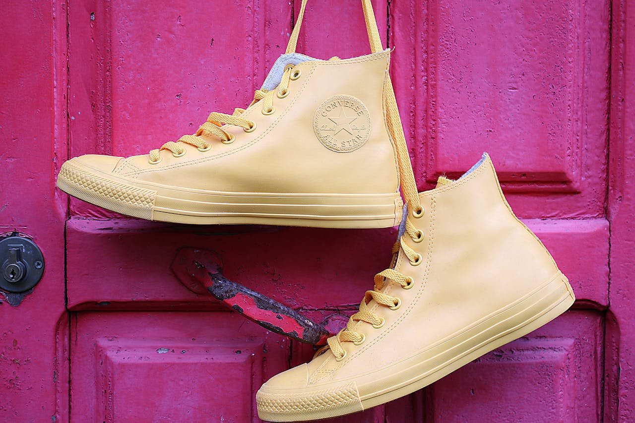 About Stylish yellow high-top sneakers hanging on a vibrant pink painted door.
